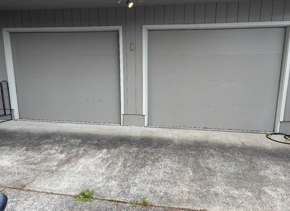 Two worn flat-panel garage doors in grey, photographed before replacement